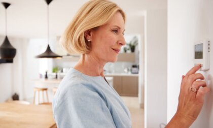 A woman adjusting a thermostat