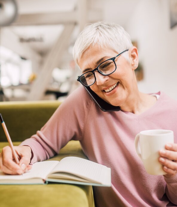 A woman talking on a phone and taking notes