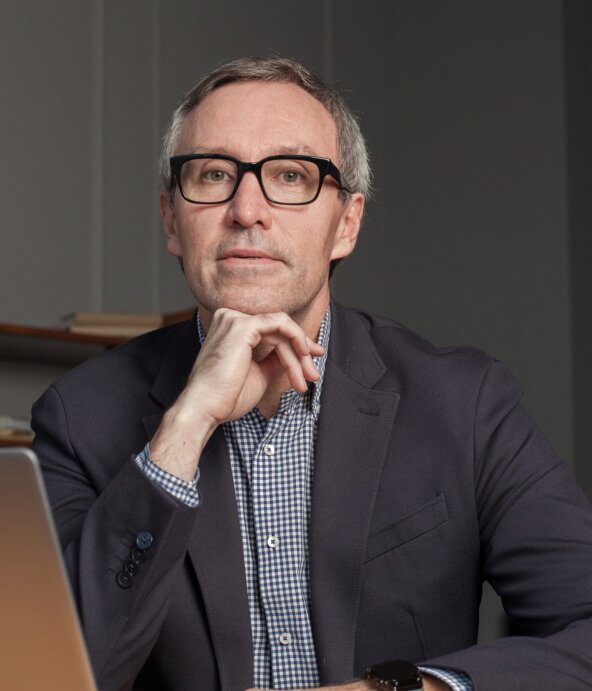 A man sitting in front of a laptop, wondering
